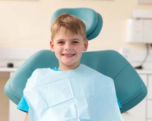 young kid smiling in a dentist chair