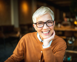 an older woman in glasses smiles for the camera