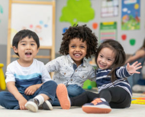 3 young children smile in a pre-k class