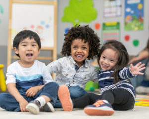 3 young children smile in a pre-k class