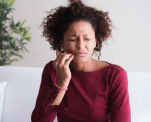 young woman clasps her jaw in pain