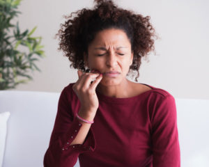 young woman clasps her jaw in pain