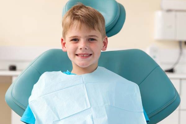 young kid smiling in a dentist chair